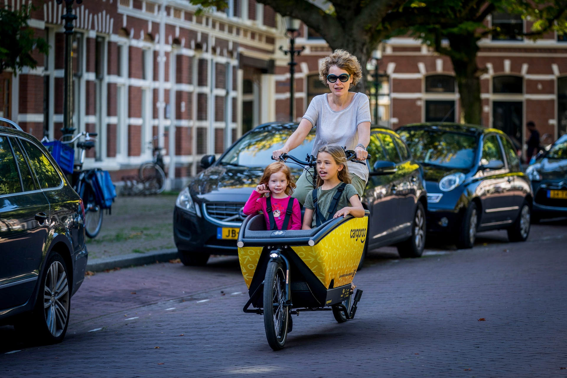 A friendly Dutch Club Captain next to a yellow Cargoroo cargo bike