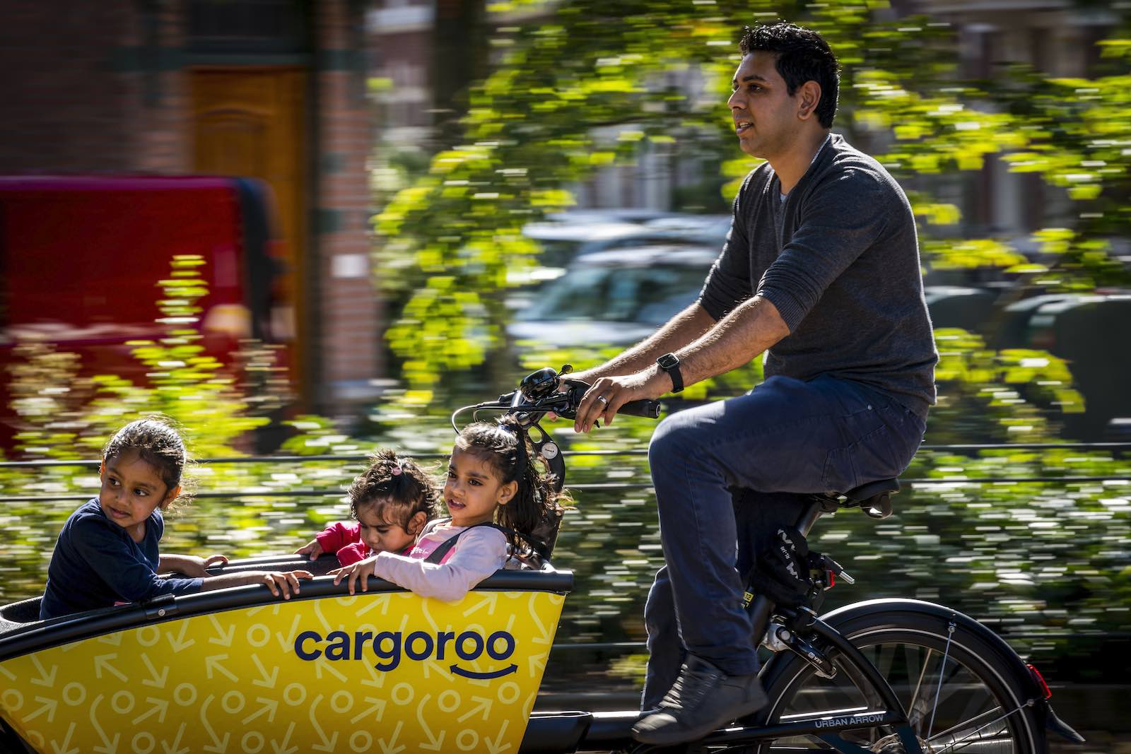 A family loads groceries into a shared cargo bike
